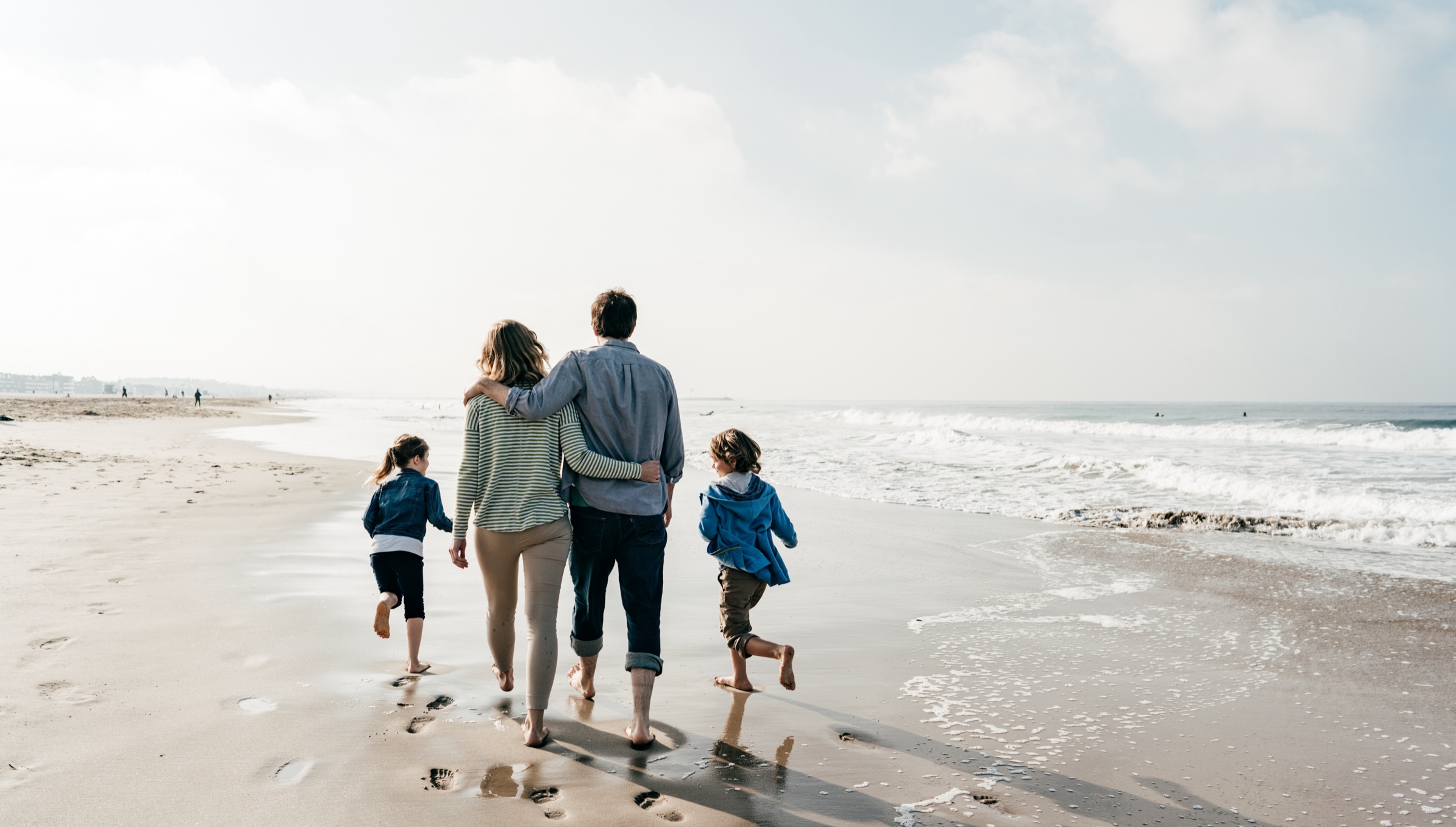 A family walking together along the shoreline — casual, everyday pace.