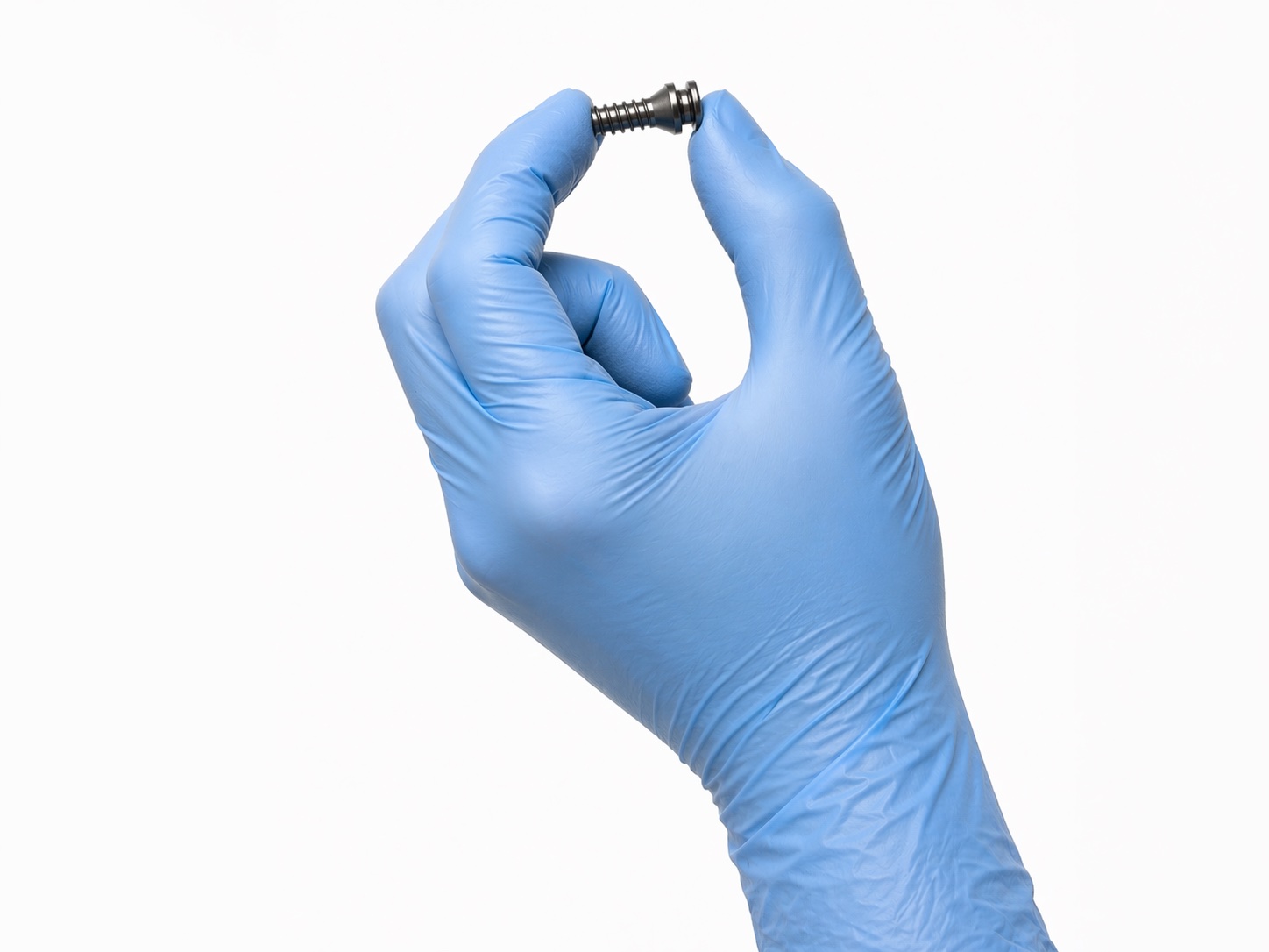 A gloved surgeon's hand holding the HyProCure&reg; titanium stent — showing its true, fingertip size.